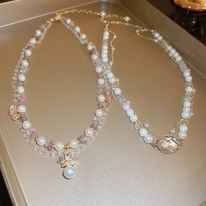 Detail view of double-layer French vintage necklace with pearls and pink crystals on gold tray