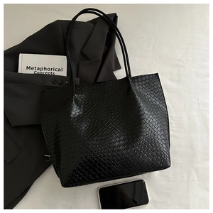 Detailed close-up of a black woven textured tote bag with long double shoulder straps