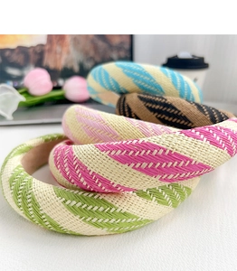 Close-up of four woven headbands in striped green, rose, brown and blue colors