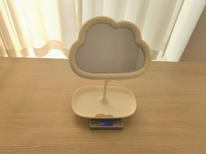 Detailed view of cloud makeup mirror on scale showing its lightweight 208g net weight
