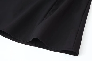 Close-up of dual-stitched hem and smooth black woven fabric on a bow dress