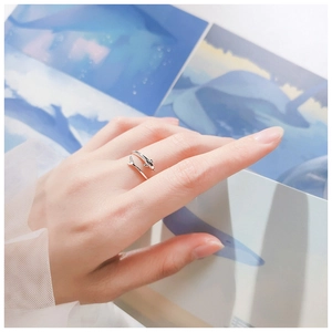 Detailed view of silver dolphin adjustable ring on hand with ocean themed backdrop