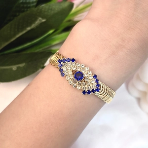 Bracelet œil porte-bonheur doré avec pierres bleues et design en spirale multicouche
