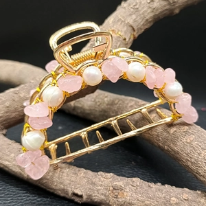 Detail of gold hair claw clip featuring pink amethyst stones and white pearls on branches