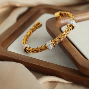 British style gold braided open bangle with sparkling pave diamond rings on silk background