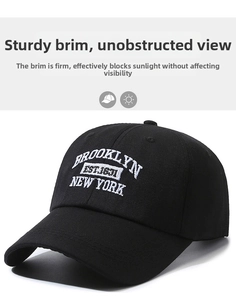 Detailed close-up of white Brooklyn embroidery on a premium black cotton baseball cap