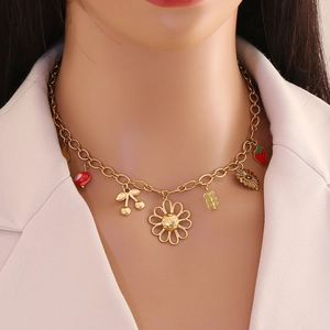 Détail d'un collier doré avec pendentifs fleur et fruits porté par un mannequin