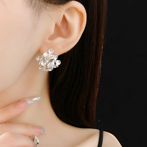 Close-up of silver floral cluster stud earrings worn by a model on black background