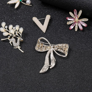 Elegant deer and floral brooches with pearls and crystals on black textured background