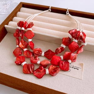 Macro detail of bohemian layered necklace with red shell charms and silver wire wrapping
