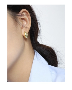 Close-up of minimalist gold teardrop earrings with a polished mirror finish on model