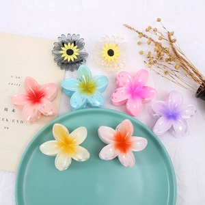 Macro detail of colorful gradient plumeria and sunflower hair claws on white fabric