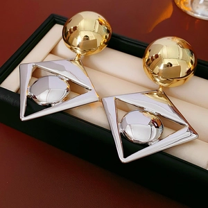Detailed view of oversized two-tone gold and silver geometric earrings in a jewelry box
