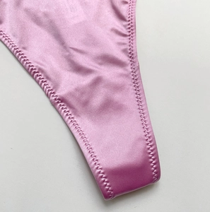 Macro detail of pink satin thong with professional wavy edge stitching and silk texture