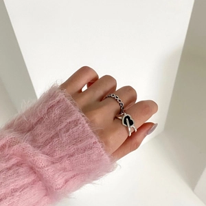 Detail view of heart-shaped silver rings worn by a model in a pink mohair sweater