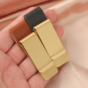 Dettaglio di fermagli per penne vintage in metallo spazzolato oro e pelle per agende