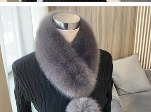 Detail shot of fluffy grey faux fur collar with pom-pom ties on a black sweater
