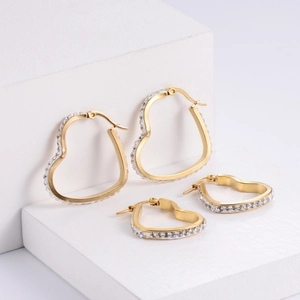Golden heart-shaped stainless steel earrings with sparkling rhinestones on white stands