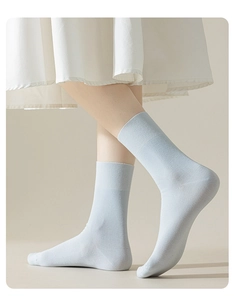 Close-up detail shot of light blue ribbed mid-tube cotton socks worn on leg model.