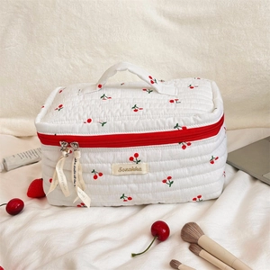 Detail of quilted cotton toiletry bag with cherry prints and red zipper closure