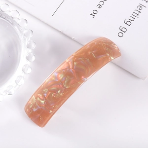 Close-up of rectangle acetate hair clip with orange iridescent shell texture and glossy finish