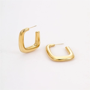 Macro shot of polished gold-plated U-shaped stainless steel earrings with shiny texture