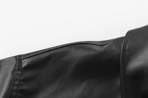 Macro shot of faux leather bomber jacket showing black grain texture and stitching