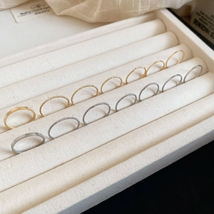 Macro view of gold and silver minimalist stackable rings on a cream fabric jewelry tray
