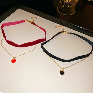 Detail of red and black velvet choker necklaces with enamel heart pendants and gold chains