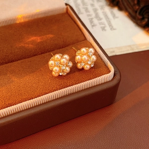Gros plan de boucles d'oreilles dorées avec perles et strass dans un écrin en velours