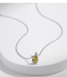 Macro view of silver water drop necklace with a sparkling yellow teardrop pendant