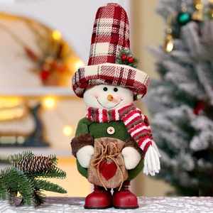 Detail view of a plush Christmas snowman doll wearing a red plaid hat and green tunic