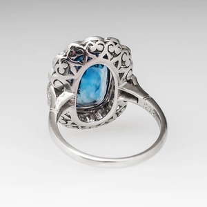 Detailed macro view of an oval blue gemstone ring with hollow metal filigree and carving