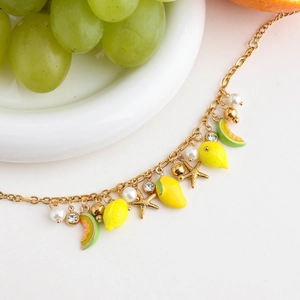 Detailed shot of gold fruit charm bracelet with lemon, starfish and pearls for summer