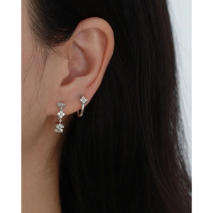 Close-up of S925 silver four-leaf clover earrings and ear cuff with sparkling zircons