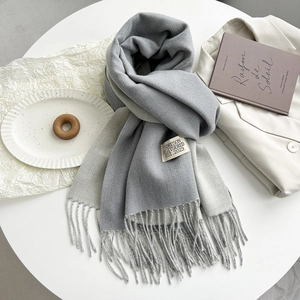 Detailed view of gray cashmere-like scarf texture with stylish fringe and woven label