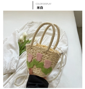 Detail der handgewebten Strohbeuteltasche in Cremeweiß mit Häkel-Tulpen und Perlenriemen