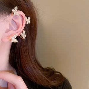 Detailed close-up of a sparkling gold butterfly ear cuff set with pavé rhinestones