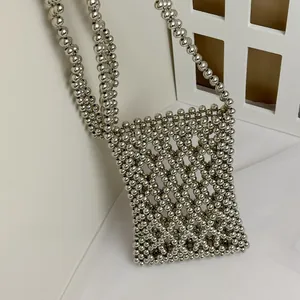 Detailed close-up of handmade silver beaded crossbody phone bag with hollow lattice design