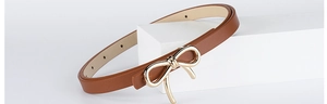 Detailed macro view of cognac PU leather belt texture and gold bow metal buckle