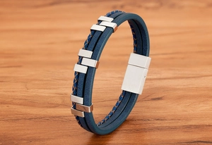 Close-up of blue multi-layer leather bracelet with silver metal and magnetic clasp on wood