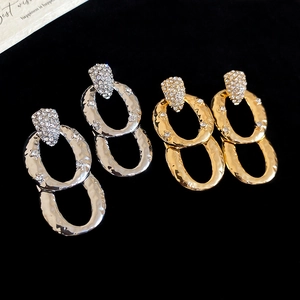 Macro detail of gold and silver layered hoop earrings with zircon pavé and hammered texture