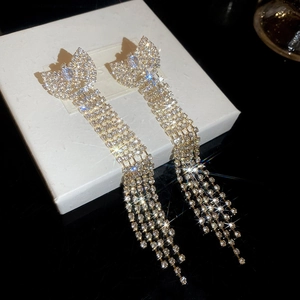 Close-up of silver tassel earrings with bow design and shimmering cubic zirconia stones