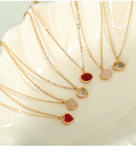 Close-up of vintage gold necklaces with red heart and oval agate pendants on a white shell plate