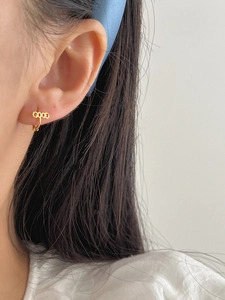 Close-up of a minimalist gold ear cuff featuring the letter GOOD design on the ear