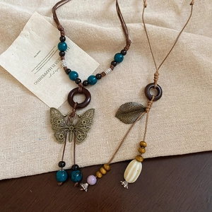 Detail of bohemian necklace featuring ceramic beads, wooden rings and butterfly pendants