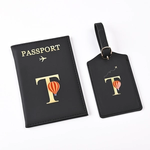 Detail of black passport holder and luggage tag set with golden letter T and balloon