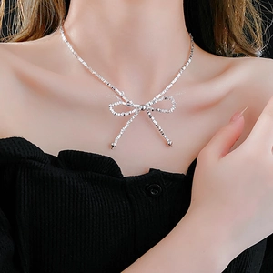 Close-up of a silver bow necklace on neck featuring a unique woven chain design