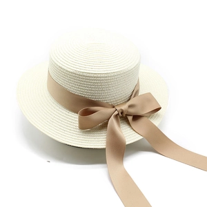 Dettaglio di un cappello di paglia bianco con elegante fiocco in nastro color kaki