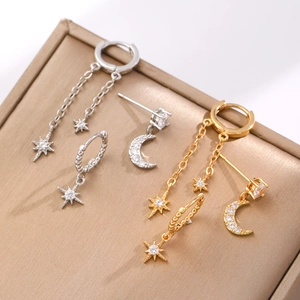 Star and moon gold earring set with white cubic zirconia on metallic surface